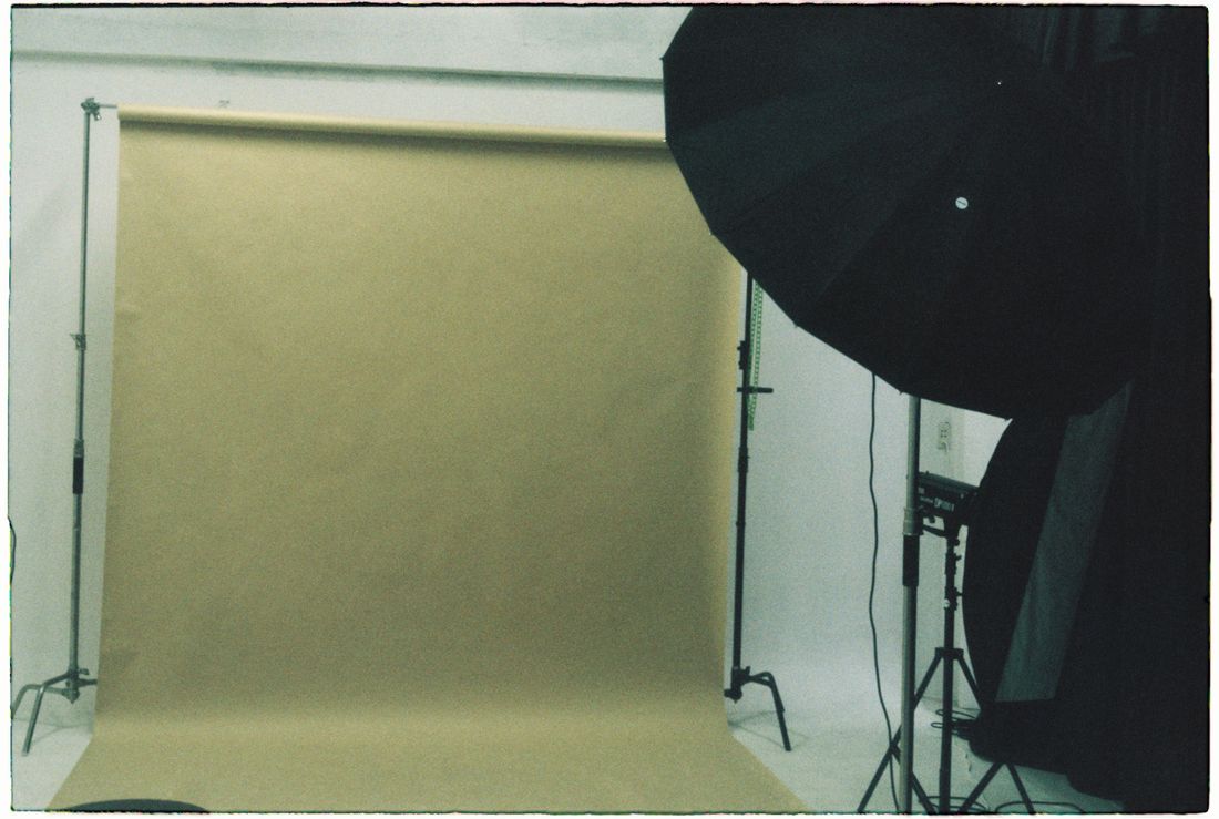 An empty photography studio with a backdrop and lighting stand set up ahead of a session