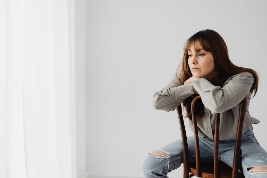 A person sitting calmly indoors, resting before a portrait session rather than posing for one