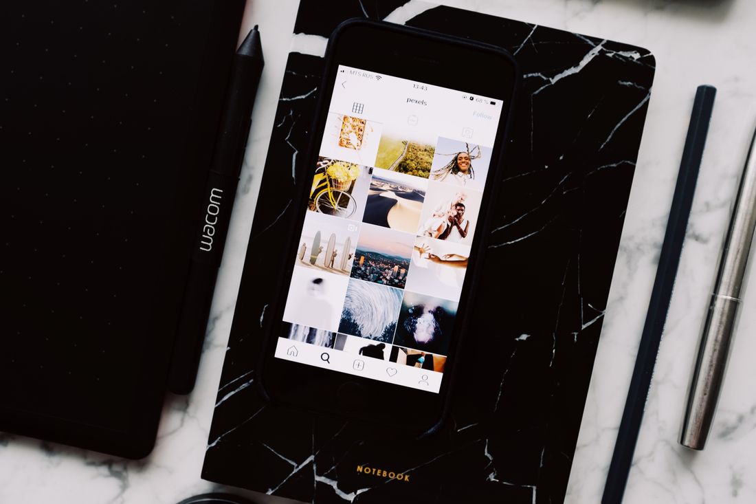 Phone displaying a photo gallery app next to a notebook, viewed from above