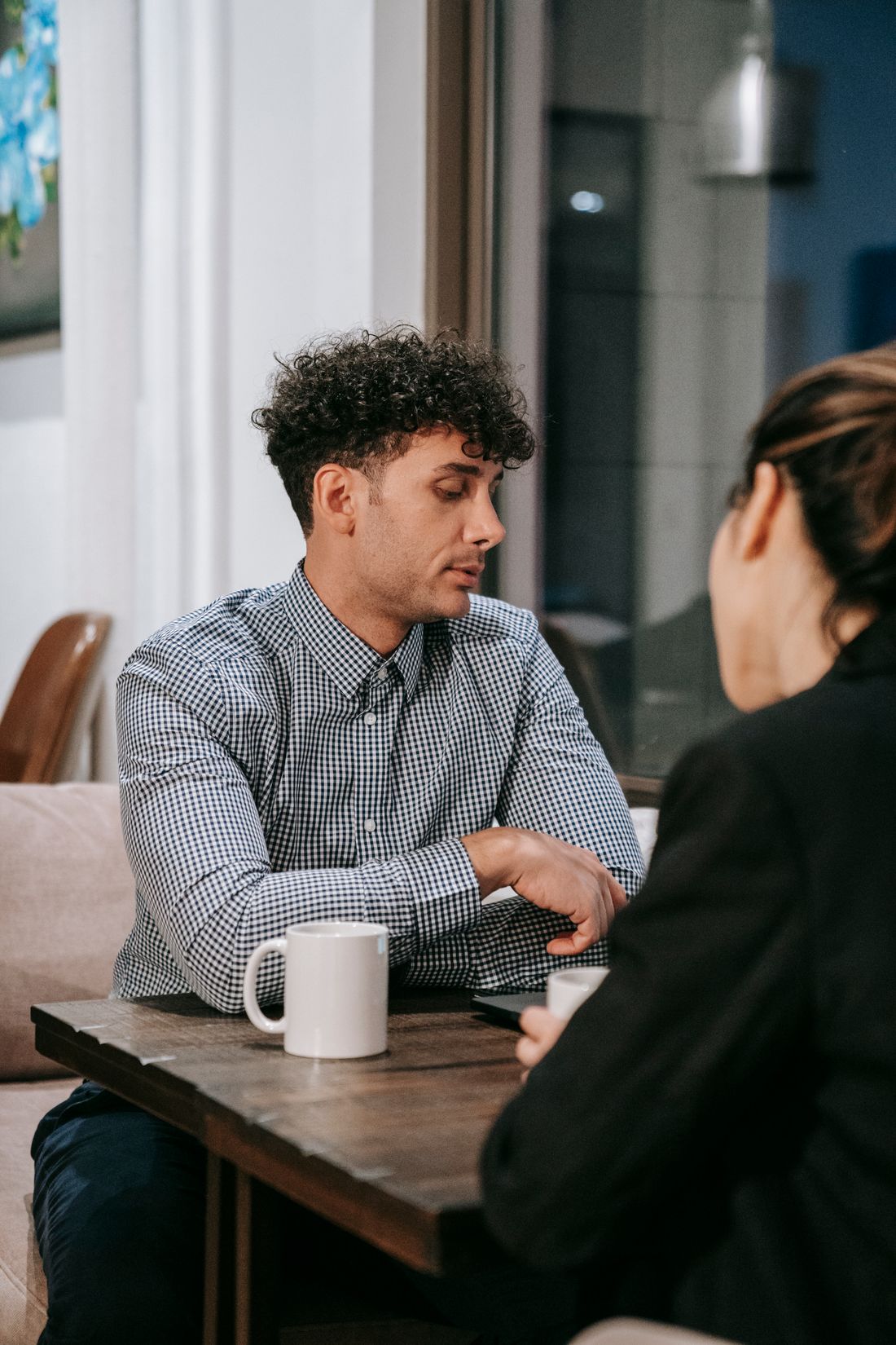 Two people in a relaxed conversation at a small table with coffee
