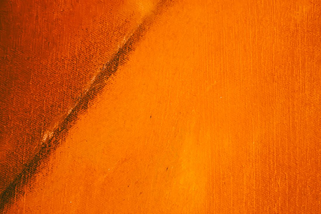 Extreme close-up of orange abstract acrylic paint texture on canvas showing visible brushstrokes