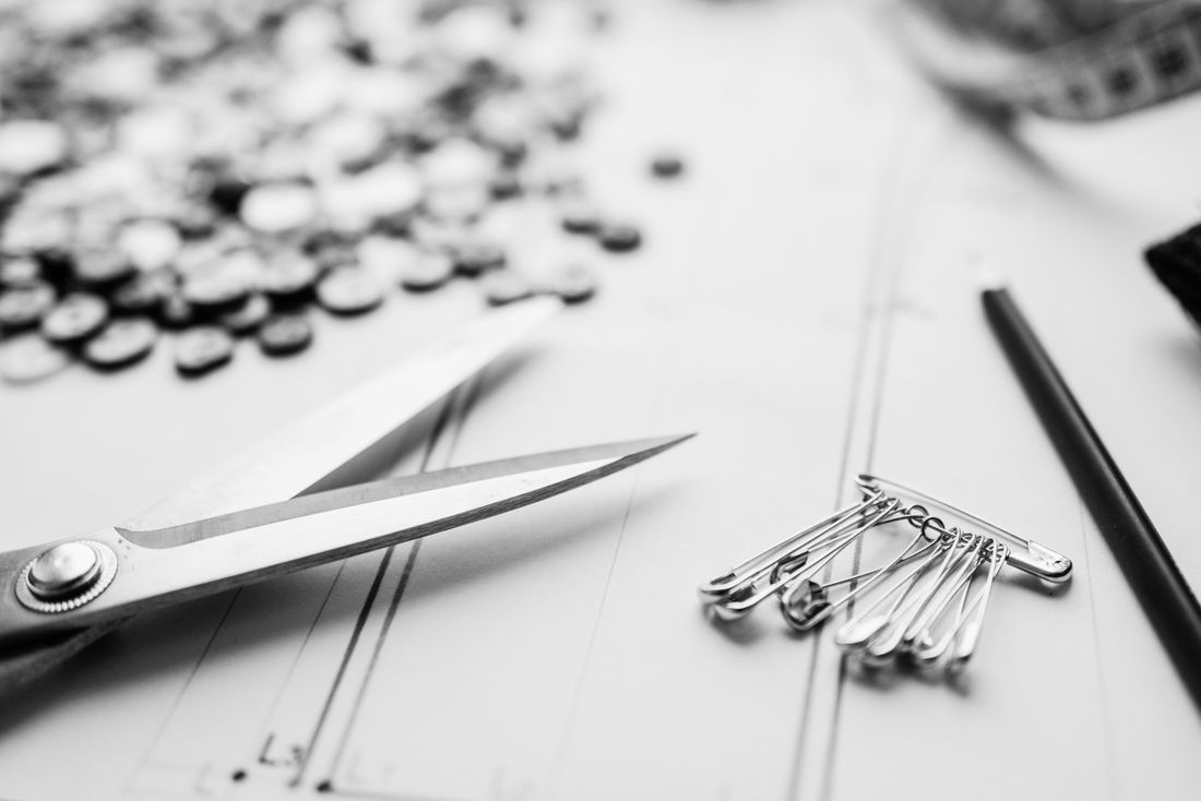 Scissors, safety pins, and buttons laid out on a worktable in a sewing workshop
