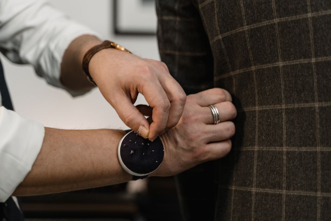 A tailor adjusting the fit of a checkered blazer on a client during a fitting session