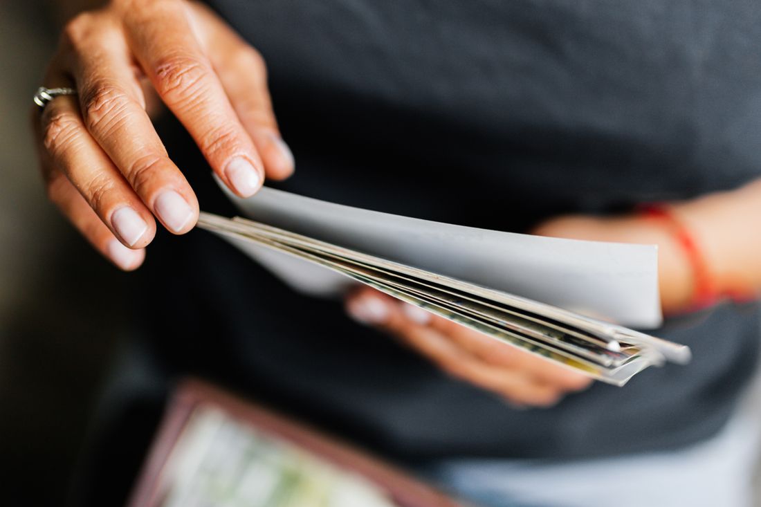 A pair of hands fanning out a small stack of printed photographs, caught mid-motion with blurred edges.
