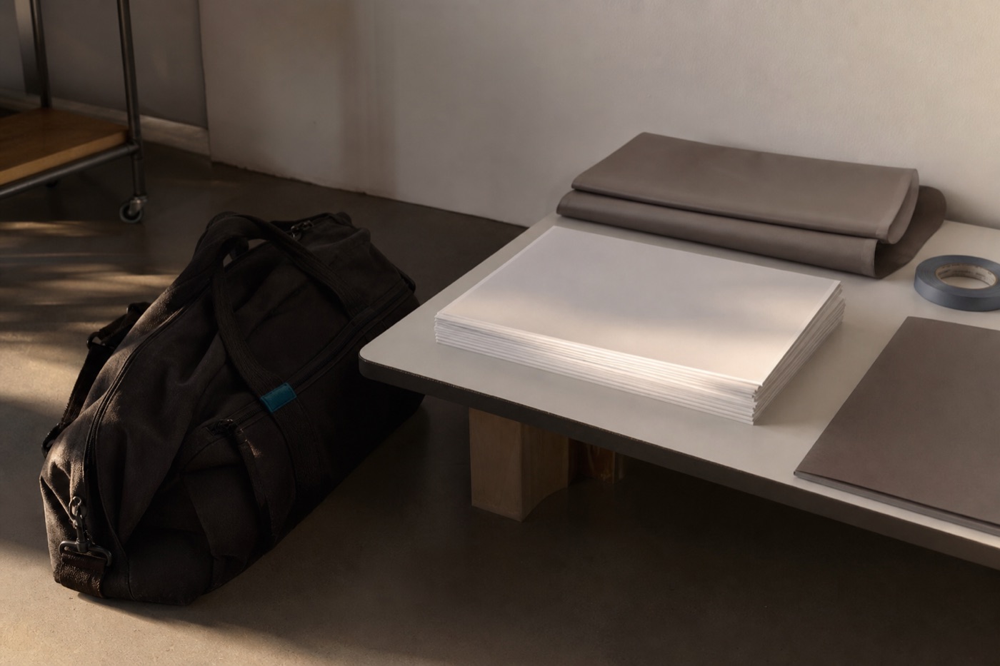 Packed black production bag beside a single stack of blank image prints and folded backdrop material