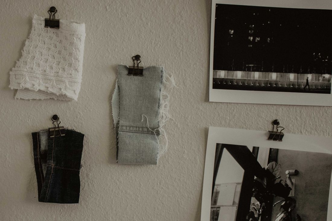 Fabric swatches pinned to a wall next to separate black-and-white reference photographs.