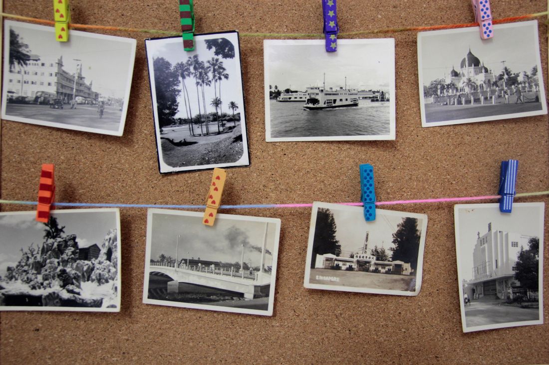 Black-and-white photographs pinned to a corkboard with colorful clothespins, organized in rows.
