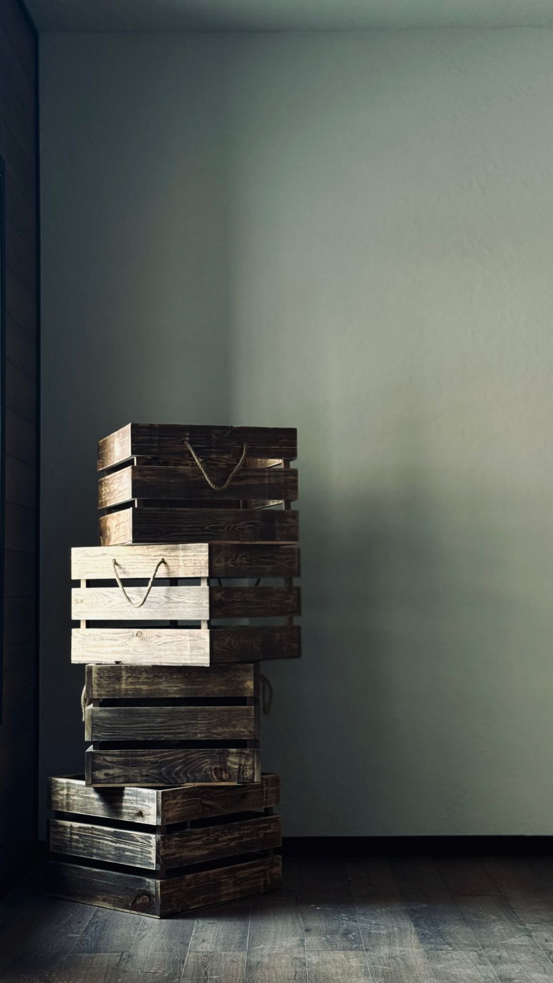 A stack of plain wooden crates standing against a bare wall indoors, no people in the frame.