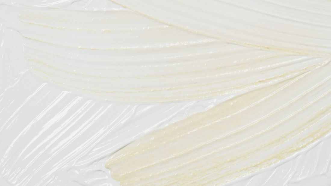 Close-up of thick cream and white acrylic brushstrokes catching light across the texture