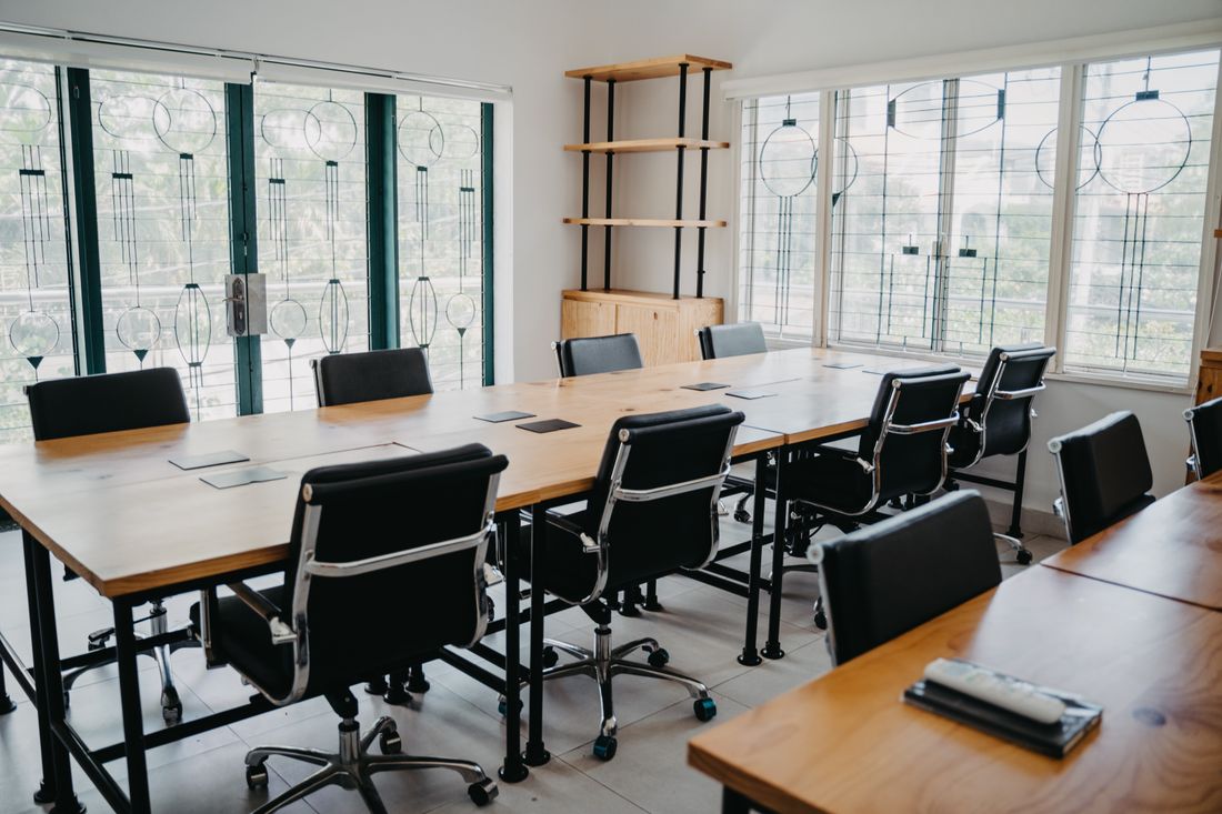 Spacious modern office conference room with black chairs and wooden tables.