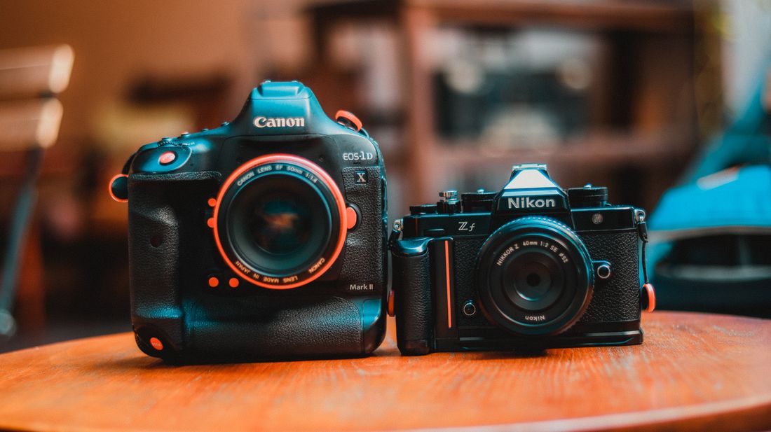 Two professional cameras from different brands placed side by side on a wooden table