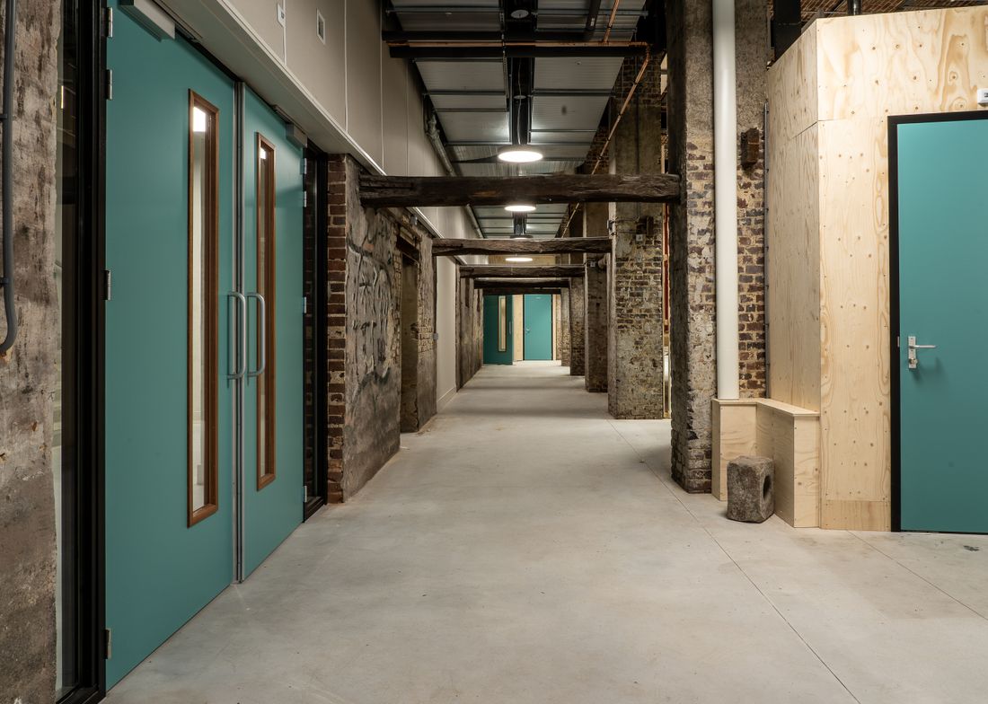 A row of studio doors along a long building corridor, representing the many stops on an open studios route.