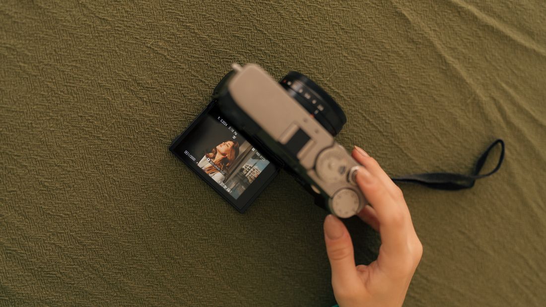 A camera held in hand, showing a portrait photo on its rear display screen