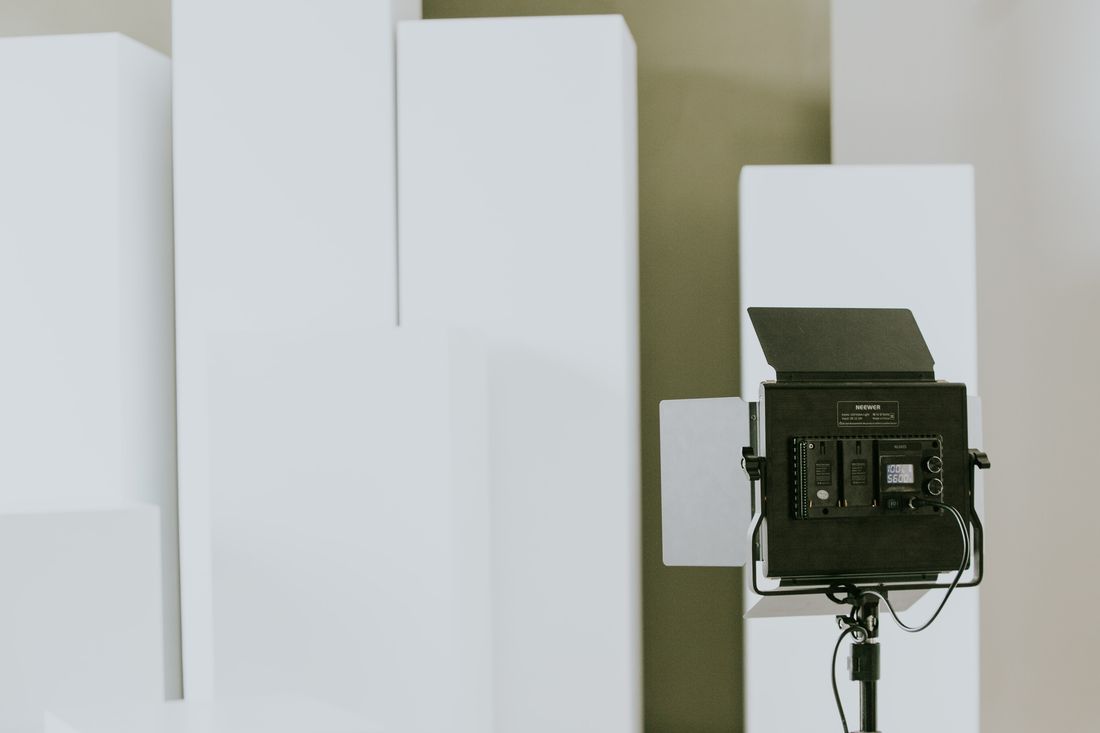 A studio light on a stand positioned in front of plain white background panels