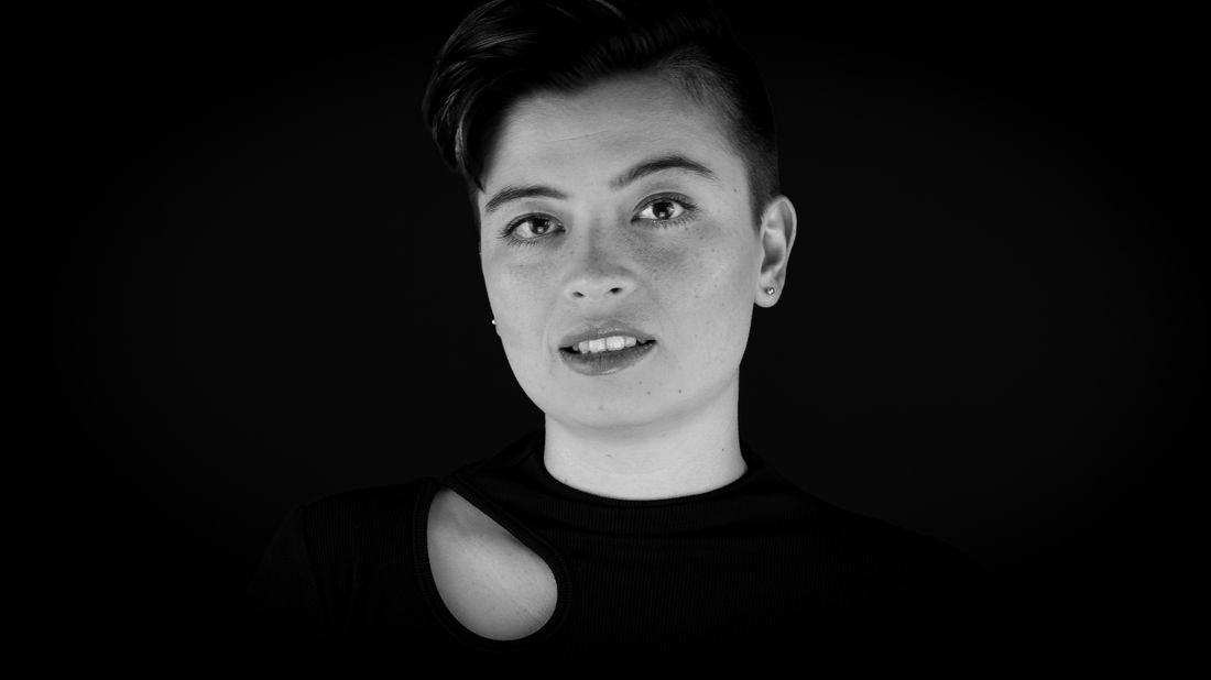 A black and white studio portrait of one person against a plain dark background