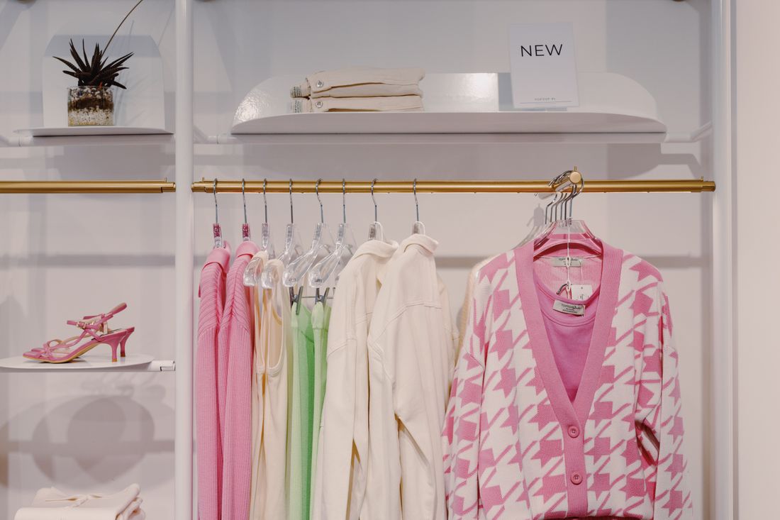 A boutique clothing rack holding pink, cream, and green garments in a coordinated but varied palette