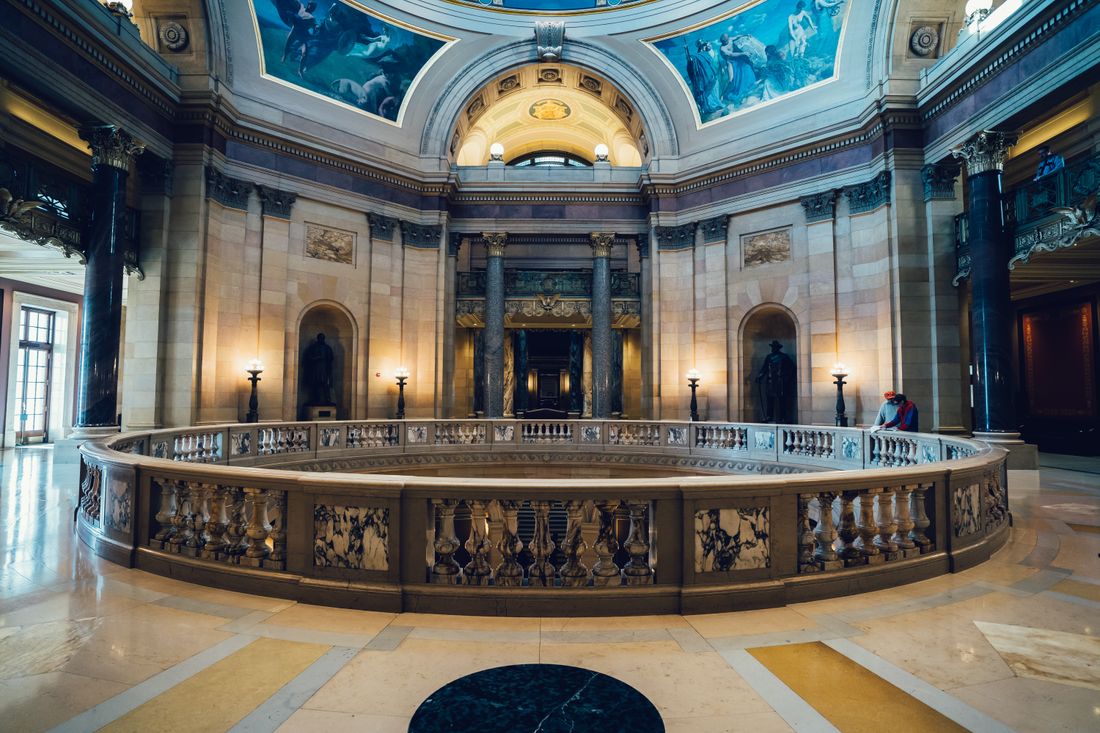 A grand ornate interior hall with a domed painted ceiling, columns, and a marble balustrade, representing a protected historic interior