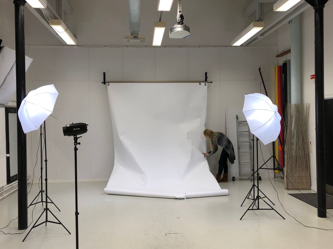 A photography studio set up with large diffused softbox lights on either side of a plain white backdrop