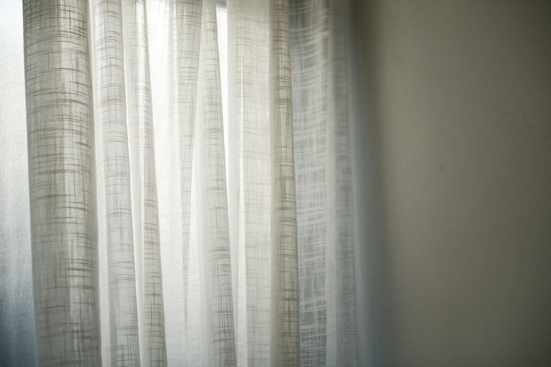 Sheer white curtains lit by soft daylight, showing translucent fabric with subtle shadow and light passing through