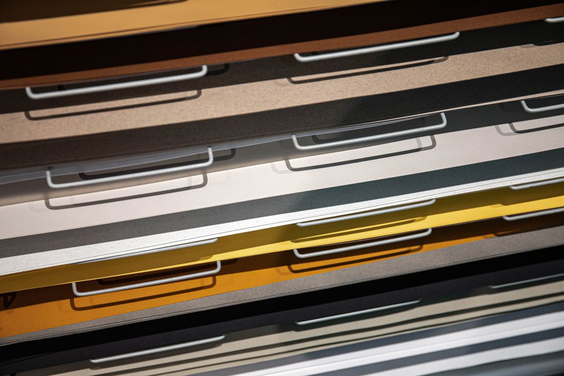 Close-up of flat storage drawers holding stacked paper sheets under bright studio lighting