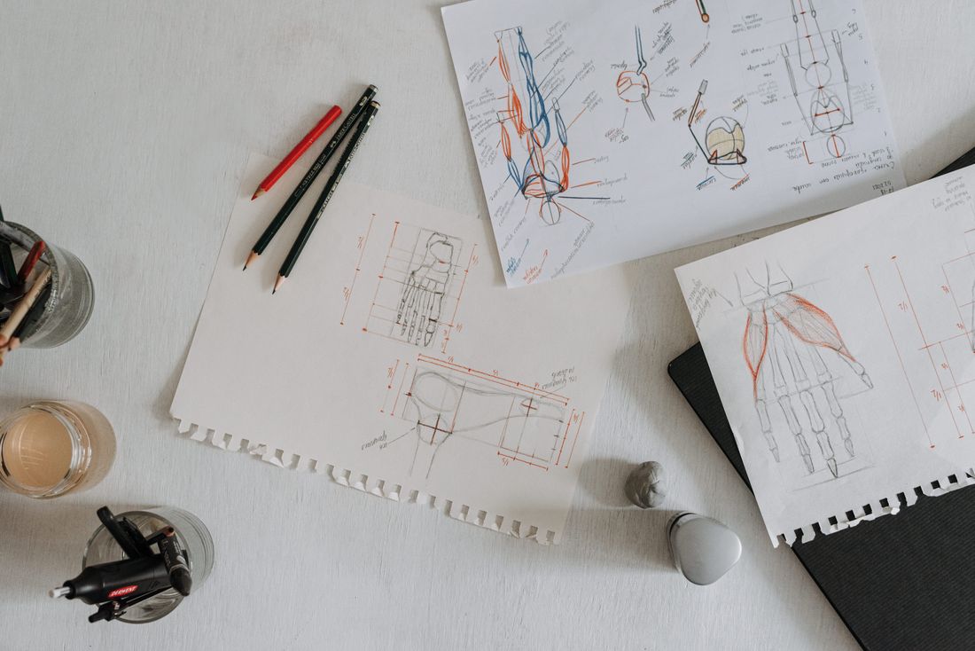 Sketches and studies spread flat across a studio desk, showing the paper's edges and surface texture