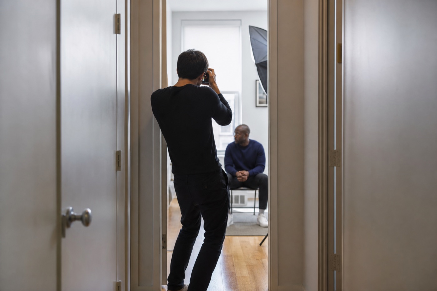 Photographer standing in a narrow hallway to gain distance from a portrait subject seated inside a small room