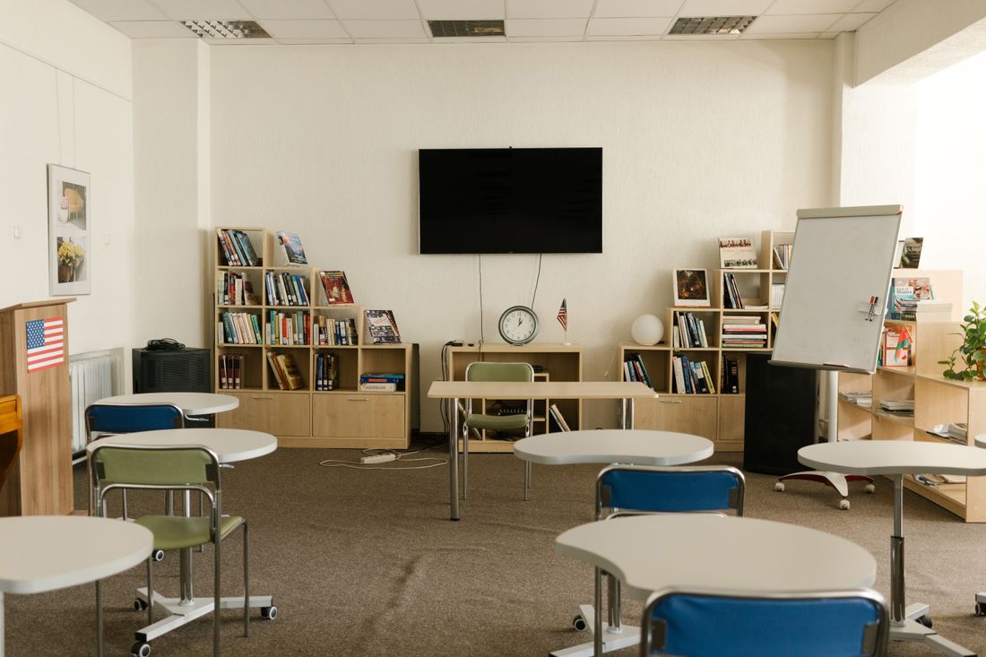 A community program room with movable tables, bookshelves and a whiteboard, empty between sessions
