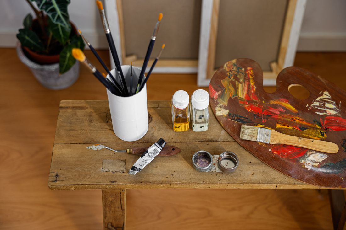 Brushes in a pot and a used palette on a wooden studio table