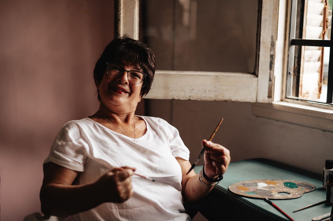 A joyful artist smiling naturally while holding a paintbrush in her studio