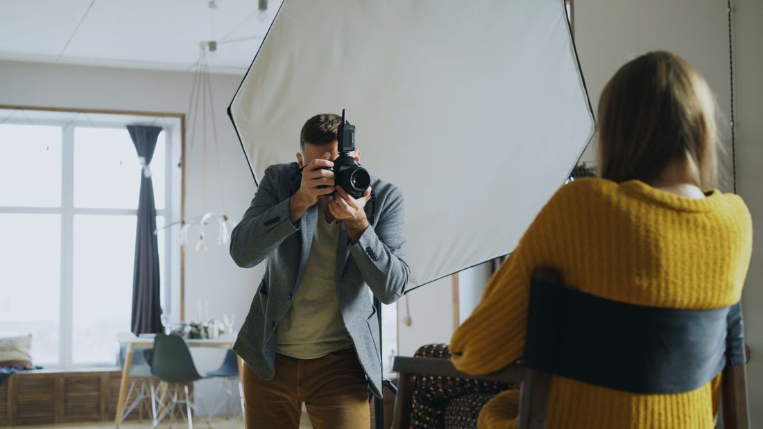A photographer taking a portrait in a studio using natural window light