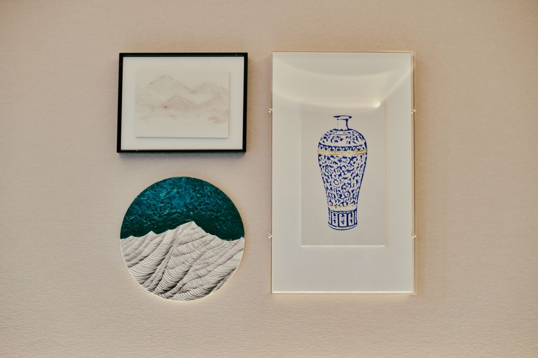 Three small framed and unframed works hung together on a plain pale wall