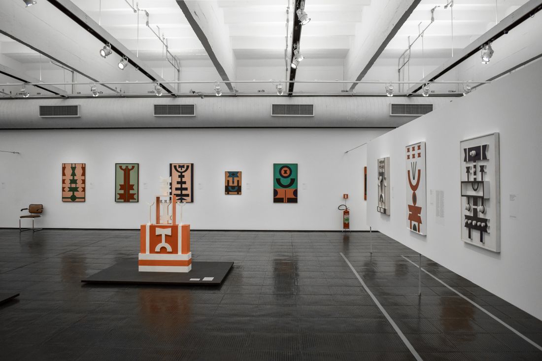 A wide, empty gallery interior with framed artwork on the walls
