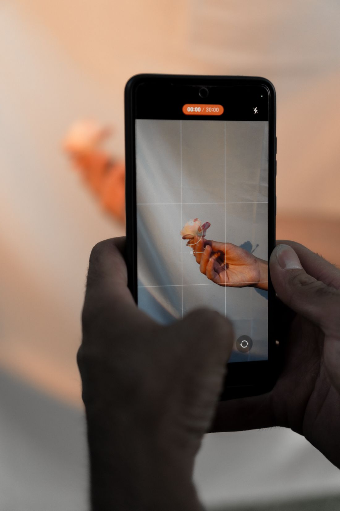 Hands holding a smartphone vertically to record a close-up scene