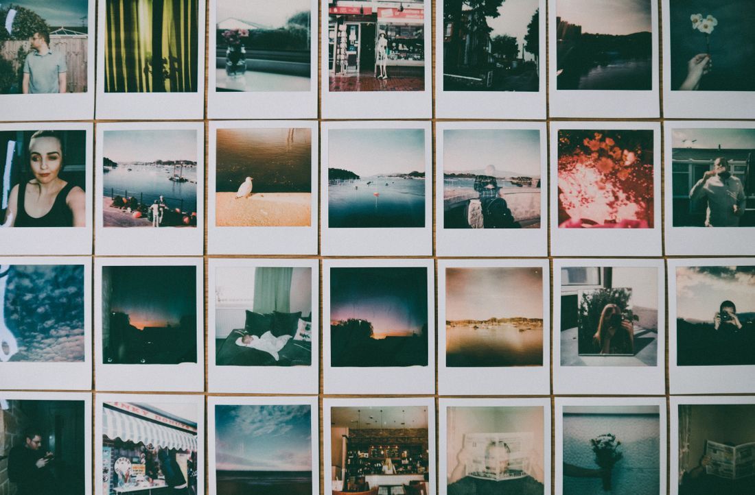 A grid of small photographic prints arranged in even rows on a pale wall