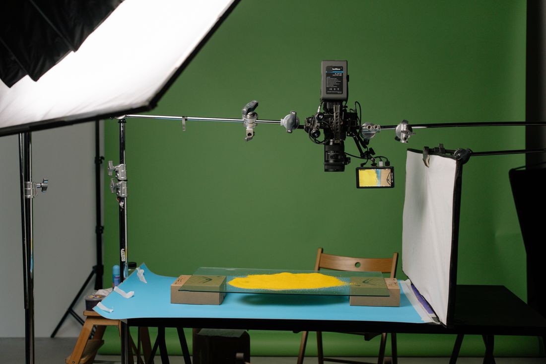An overhead camera rig on a boom arm positioned above a table for photographing a flat subject under studio lighting