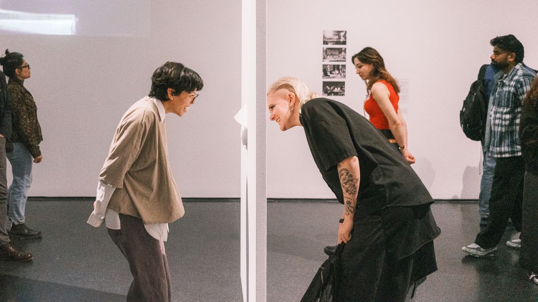Visitors standing and talking in front of an art installation at an indoor exhibition
