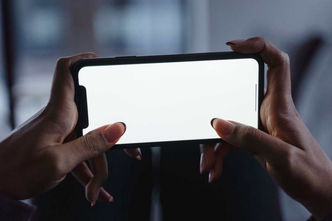 Two hands holding a smartphone horizontally with a blank screen
