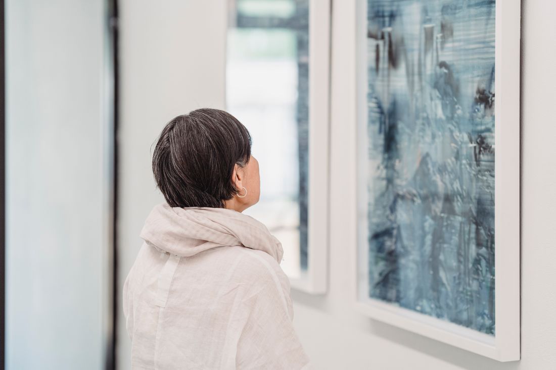 A visitor viewing framed abstract paintings on a gallery wall