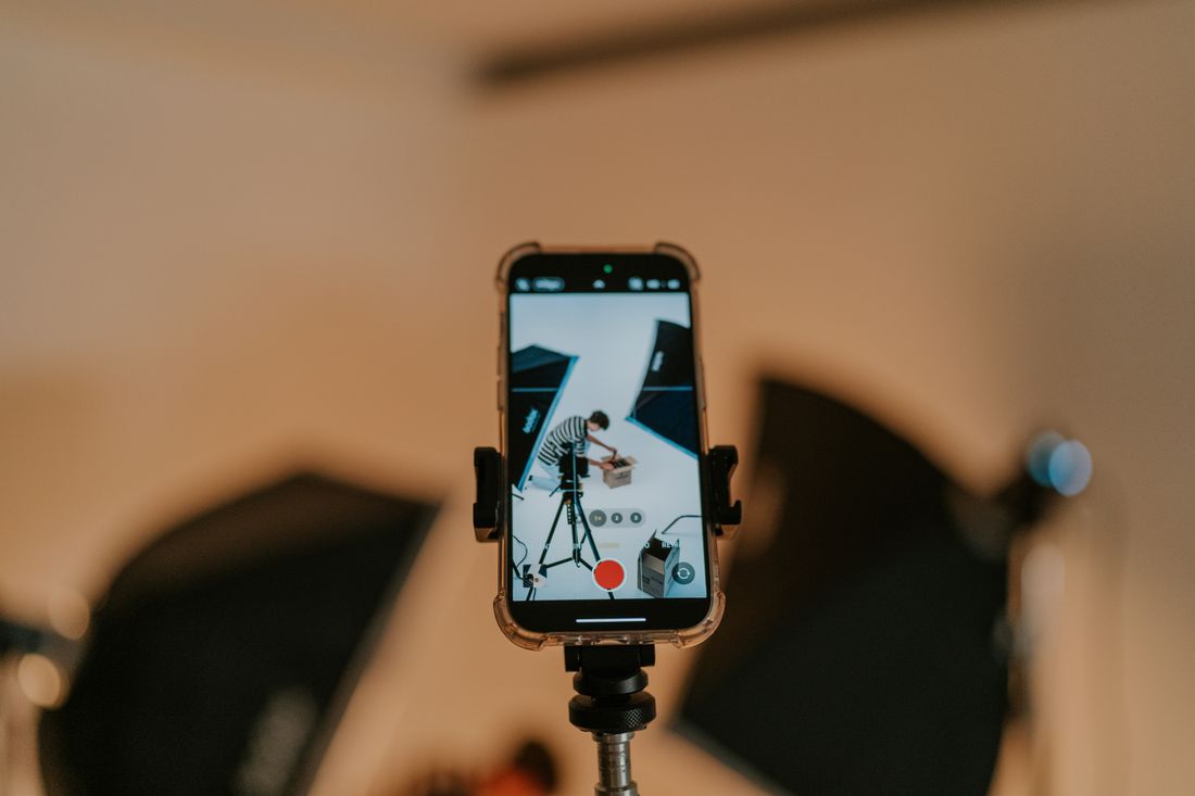A smartphone mounted on a tripod recording video in a studio setting