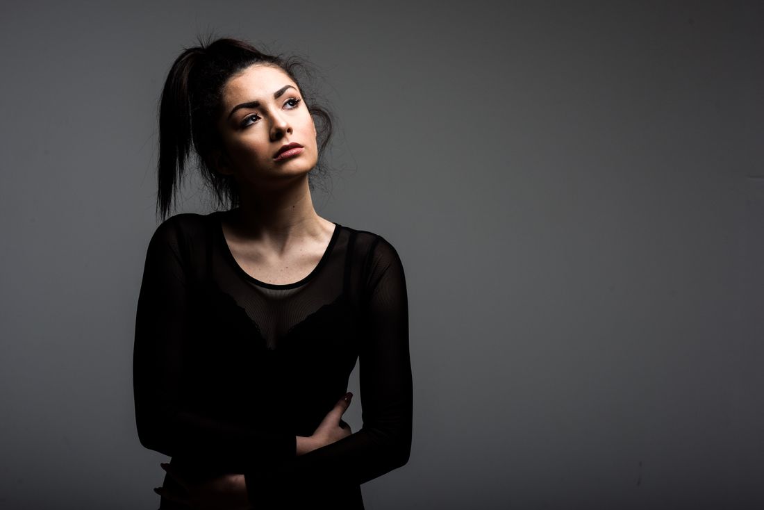 A close portrait of a woman against a plain gray studio background, with no artwork in frame