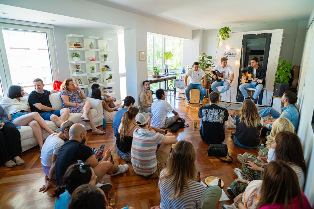 A small seated audience listening closely in an intimate room during a low-key gathering
