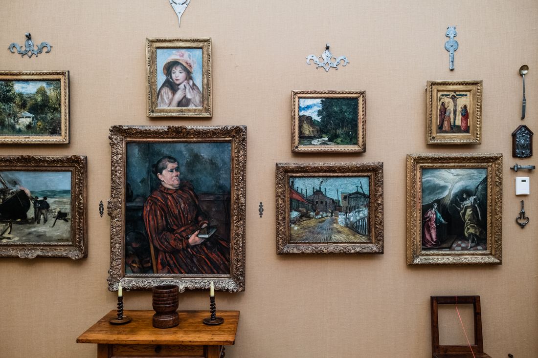 A gallery wall with a grid of framed paintings arranged closely together