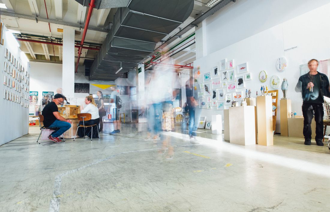 Blurred motion of visitors moving through a gallery space during a busy opening