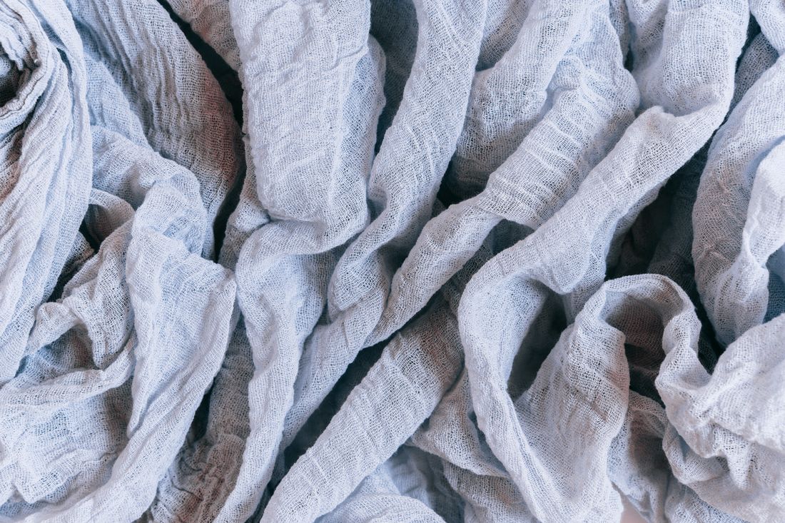 A close, detailed view of pale crumpled linen fabric showing its natural creases and loose weave