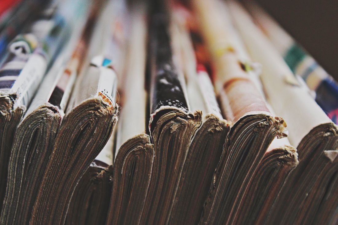 A row of magazines stacked together with their fanned, worn page edges facing the camera.