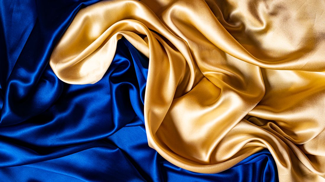 Blue and gold silk fabric draped and gathered into soft, flowing folds