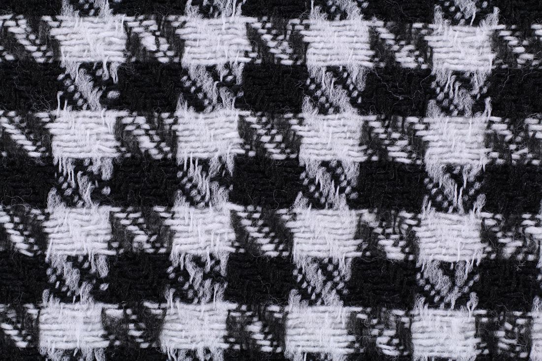 A close-up of black and white houndstooth fabric weave, showing its fine, tightly repeating pattern