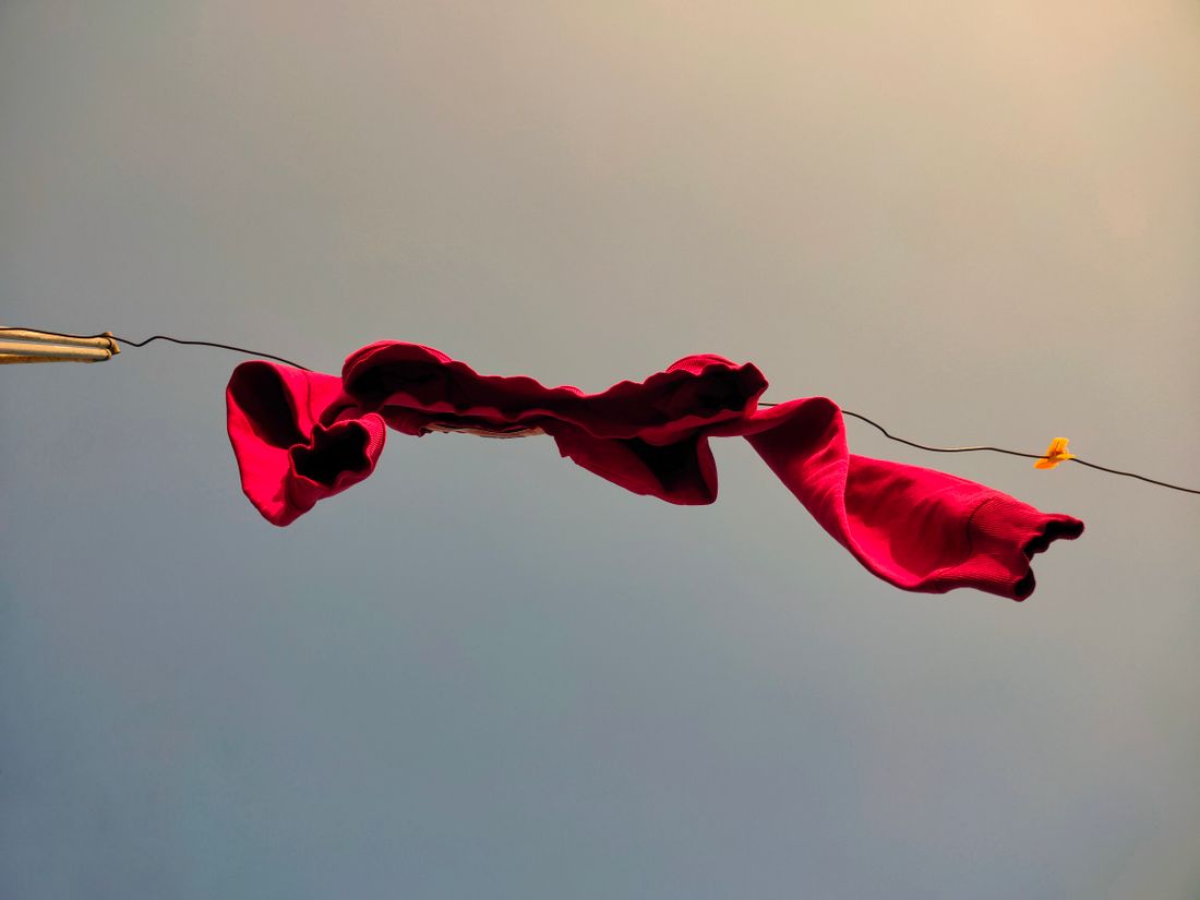 A red fabric panel fluttering on a line against a plain sky, showing wind movement