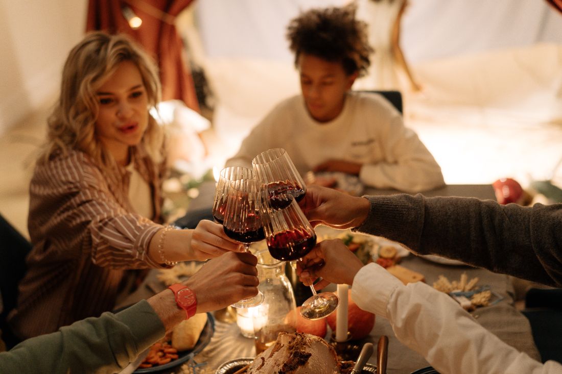 A small group raising wine glasses in a toast during a low-lit indoor dinner