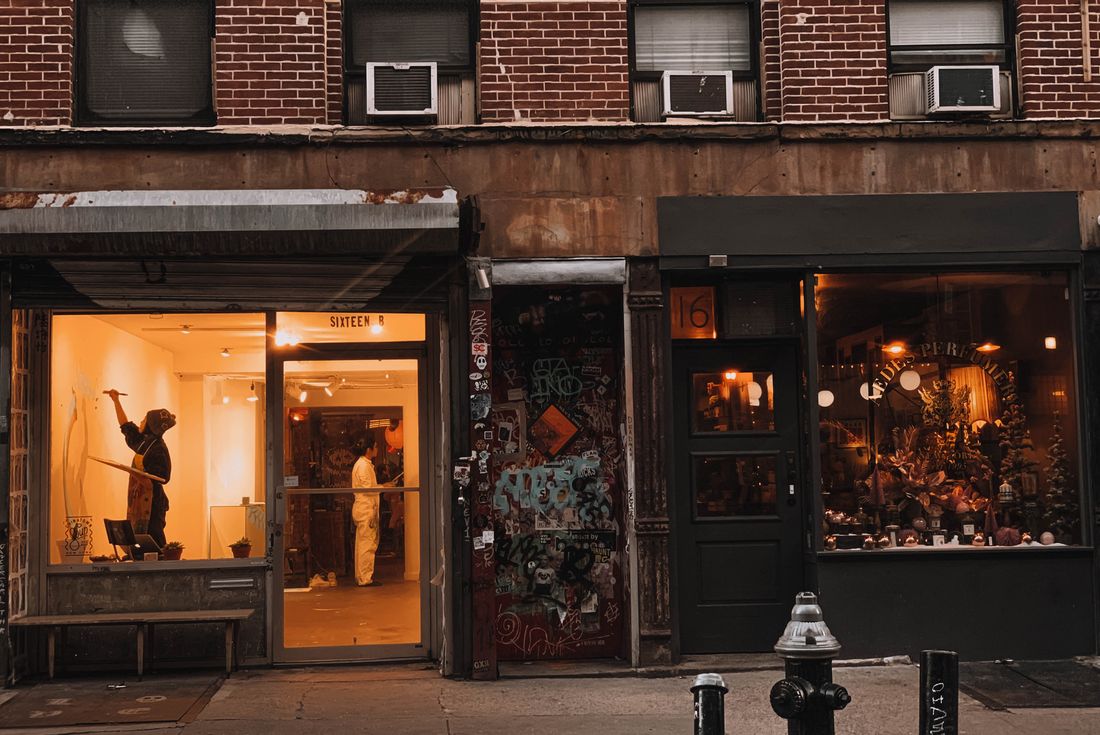 A NYC gallery storefront and florist display glowing at dusk, evoking a night when several openings happen at once